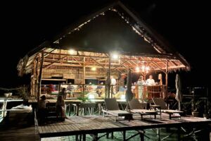 face of a wooden papuan statue with Papua Explorers main jetty in the backgound